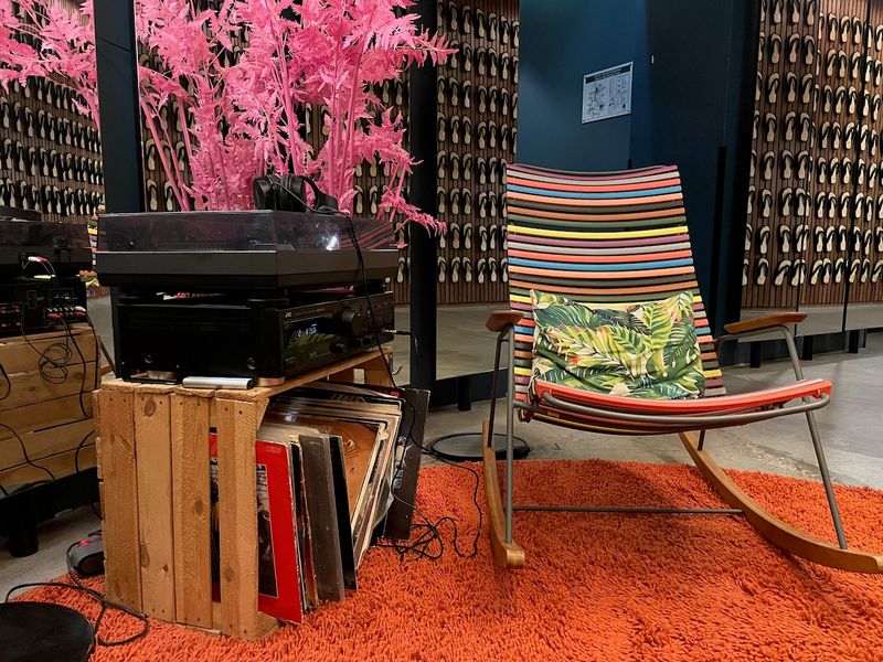 A rocking chair next to a vinyl player in a cosy and colorful hotel lobby